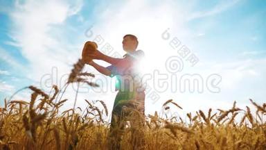 老农夫剪影面包师拿着一个金色的面包和面包在成熟的麦田里对着蓝天。慢动作